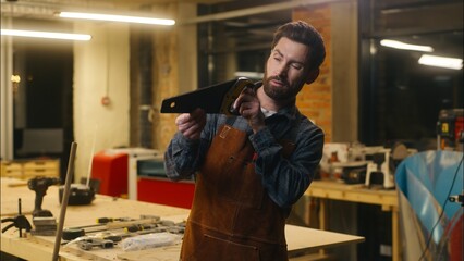 Caucasian carpenter repairman worker wood master examining saw male craftsman inspect instrument in...