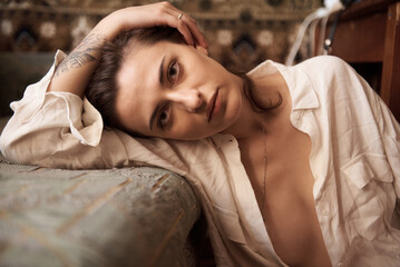 A pensive woman in a white shirt resting and looking at the camera.