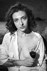 A young woman with a glass of red wine in a sensual black and white portrait.