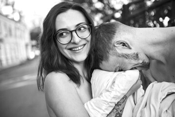 A smiling woman embraces a man, sharing a tender moment together in a black and white photo.