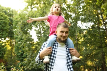 Fototapeta premium Happy Father's Day. Dad and his little daughter spending time together in park, low angle view