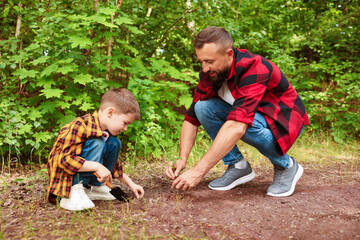 Father and his son planting tree into soil outdoors