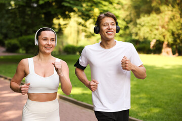 Sporty couple with headphones running in park