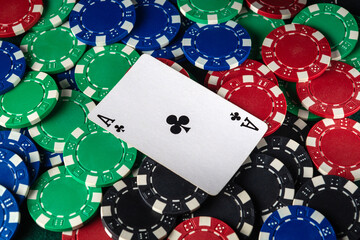 A vibrant assortment of colorful poker chips surrounds an Ace of Clubs card, suggesting an ongoing...