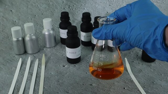 chemical beaker , flask is on white table with blotting paper , fragrance bottle and essential oil bottle are used to blend the nice scent for making perfume and candle by perfumer in the laboratory