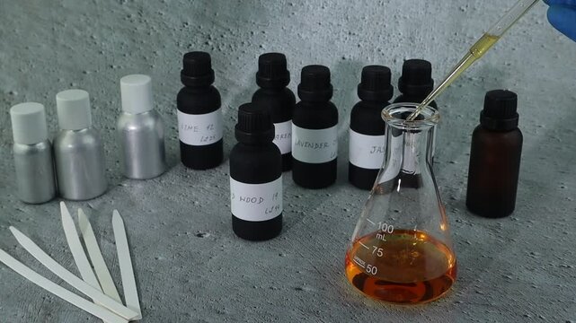 chemical beaker , flask is on white table with blotting paper , fragrance bottle and essential oil bottle are used to blend the nice scent for making perfume and candle by perfumer in the laboratory