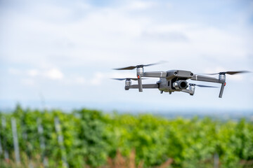 Flying Drone in Vineyard Captured in Sharp Focus – Modern UAV with Camera Hovering Mid-Air,...