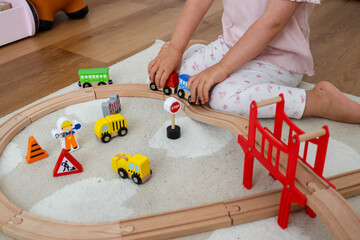 Little Girl Playing with Colorful Toy Train Set on Wooden Track