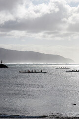 Outrigger canoe paddling at Waialua Bay at the island of Oahu, Hawaii, USA against backlight