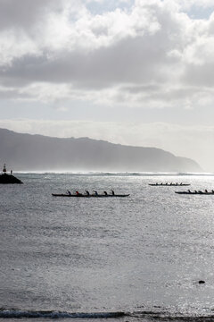 Outrigger canoe paddling at Waialua Bay at the island of Oahu, Hawaii, USA against backlight