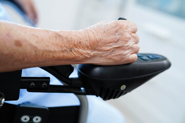 Asian elderly disability woman patient use joystick electric wheelchair in hospital.