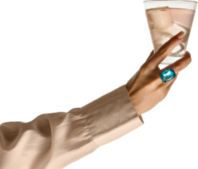 Styled hold. Female hand with bright blue gemstone ring gracefully lifts glass with pink beverage and large ice cubes on transparent background. Concept of elegance, celebration, refreshment.