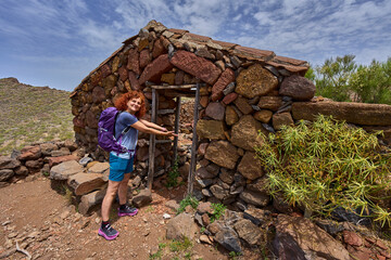 Hiker showing stone shelter in Teno