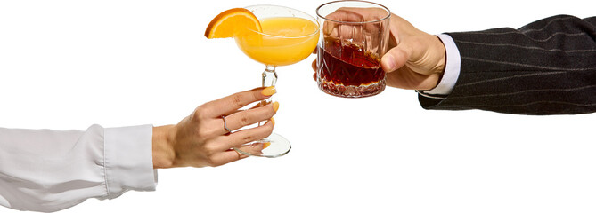 Female and male hands clinking cocktails orange drink in coupe glass with slice of citrus and dark liquor in faceted tumbler. Transparent background. Concept of toast, party, elegance, contrast.