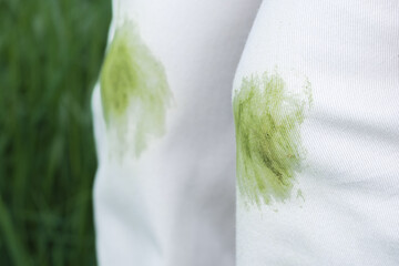 Close up of dirty grass stains on white jeans during summer activity. Clothing care or stain...