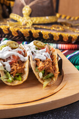 Mexican tacos al pastor with jalapeños, lettuce, and white sauce on wooden tray