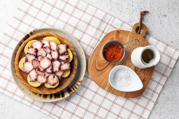Octopus dish with potatoes, paprika, salt, and olive oil on checkered tablecloth