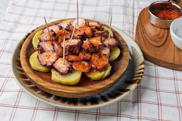Pulpo a la gallega, spanish octopus with paprika, on wooden plate with potatoes