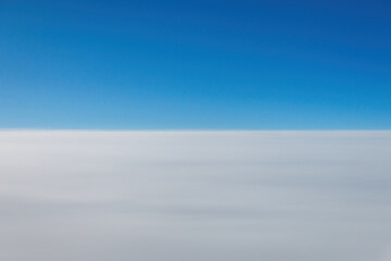 Minimalist view from above the clouds with a clear blue sky and soft white layer below