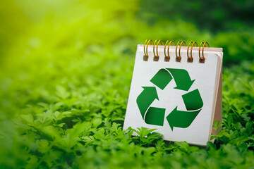 Green recycling symbol on small calendar with fresh green grass background. Concepts of reducing and reusing, environmentally friendly products, CSR, zero waste. with copy space