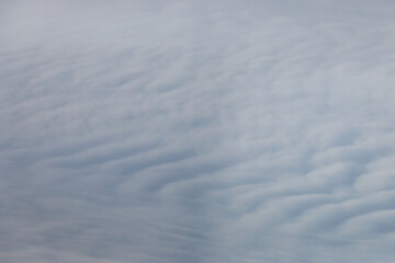 Aerial view of gently rippling cloud formations, resembling waves in the sky