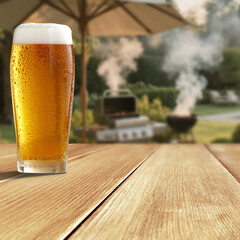 Glass of beer on wooden garden table – backyard relaxation at home. In the blurred background, a...