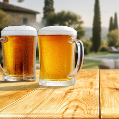 Glass of beer on wooden garden table – backyard relaxation at home. In the blurred background, a lush green garden and barbecue grill and patio area with outdoor furniture behind a house.