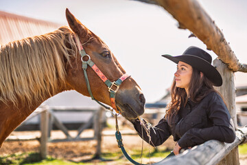 woman cowgirl, stands next to her horse in summer season