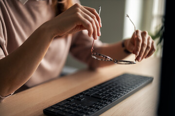 Person Adjusting Glasses While Using Keyboard at Office Desk