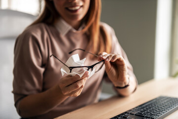 Woman Cleaning Glasses With Cloth at Work Desk