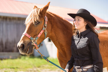 woman cowgirl, stands next to her horse in summer season