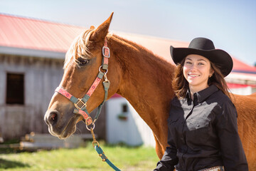 woman cowgirl, stands next to her horse in summer season