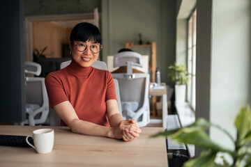 Confident Professional Woman Smiling at Desk in Bright Modern Office Space