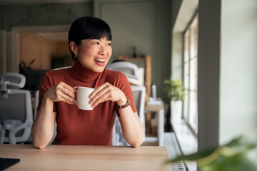 Smiling Woman Enjoying Coffee in a Cozy Work Environment
