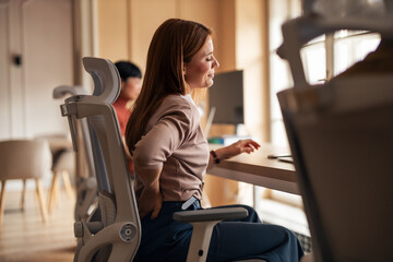 Woman Experiencing Back Pain in Modern Office Setting