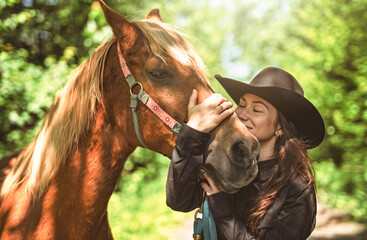woman cowgirl, stands next to her horse in summer season