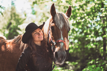 woman cowgirl, stands next to her horse in summer season