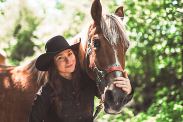 woman cowgirl, stands next to her horse in summer season