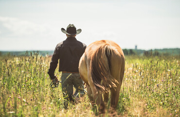 cowboy, stands next to her horse in summer season