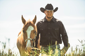 cowboy, stands next to her horse in summer season