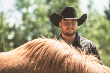 cowboy, stands next to her horse in summer season