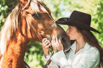 woman cowgirl, stands next to her horse in summer season