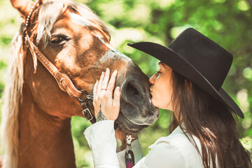 woman cowgirl, stands next to her horse in summer season
