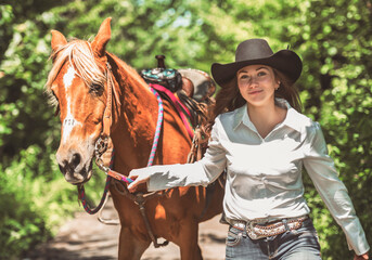 woman cowgirl, stands next to her horse in summer season
