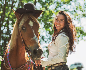 woman cowgirl, stands next to her horse in summer season