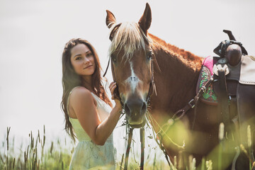 woman cowgirl, stands next to her horse in summer season