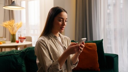 Caucasian woman using mobile phone at home concentrated girl female chatting texting smartphone...