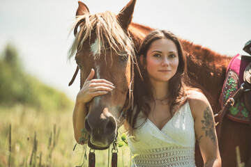 woman cowgirl, stands next to her horse in summer season