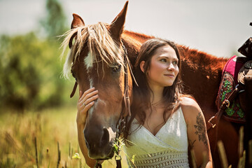woman cowgirl, stands next to her horse in summer season