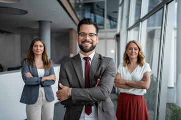 Confident business team smiling with arms crossed in modern office